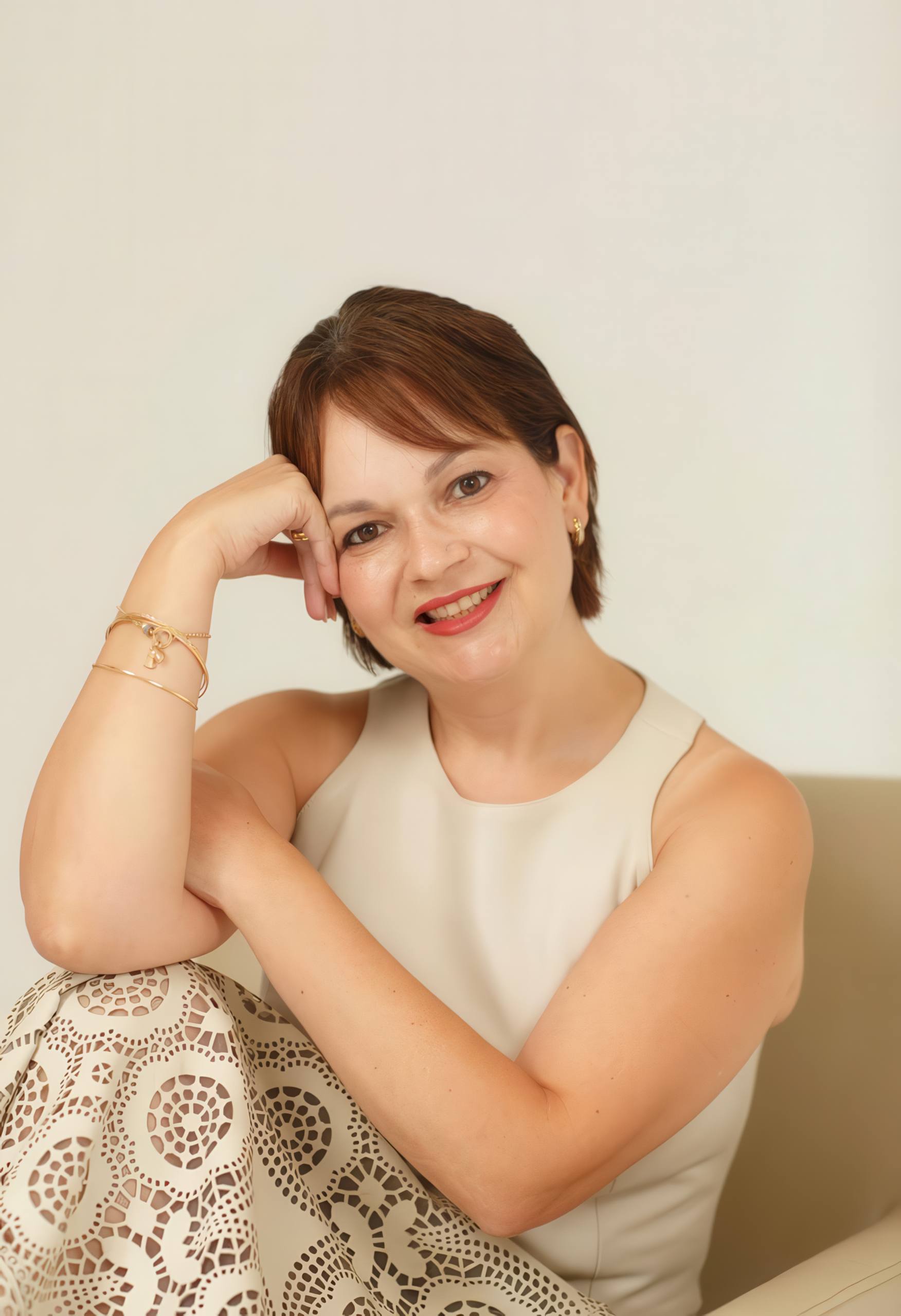 Dra. Yanne Batista sentada, sorrindo, com a cabeça apoiada na mão.